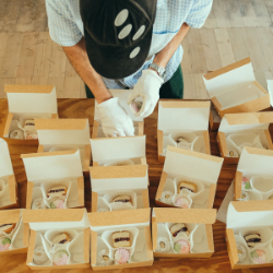 Person packing different kinds of sweet biscuits into cardboard gift boxes