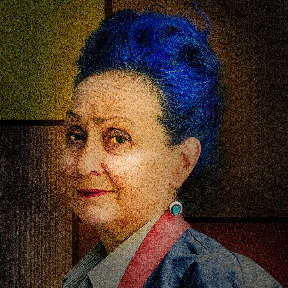 An older woman with Blue Hair looking at the camera side on.