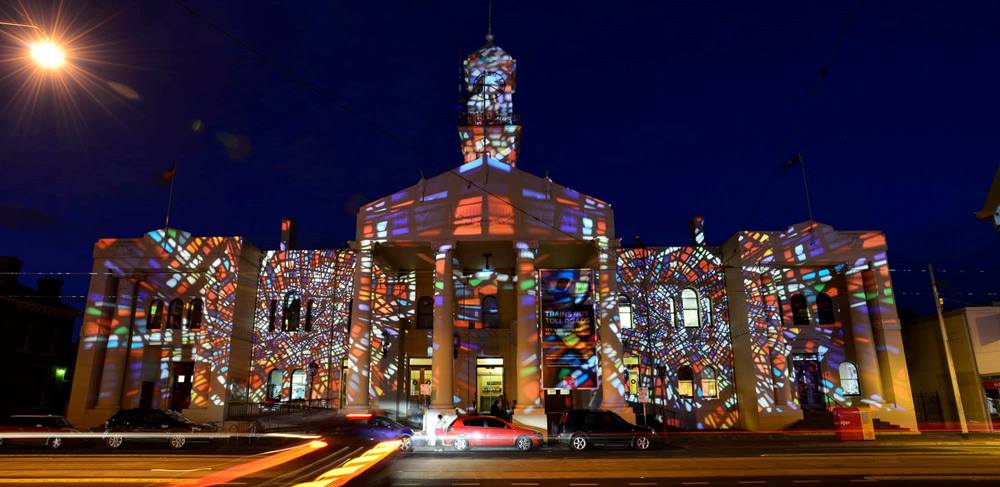 A photo of Richmond Town Hall, with projections of a stained glass window on the heritage façade of the building