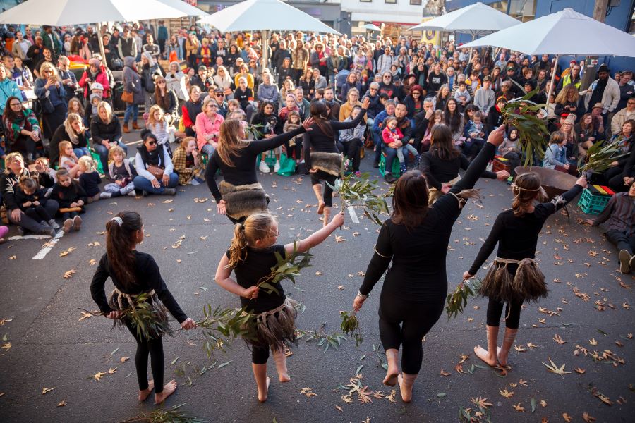 Djirri Djirri Dance Group at Smith Street Dreaming, 2019. Four dancers facing a crowd of people. The dancers are wearing black with fur elements. 