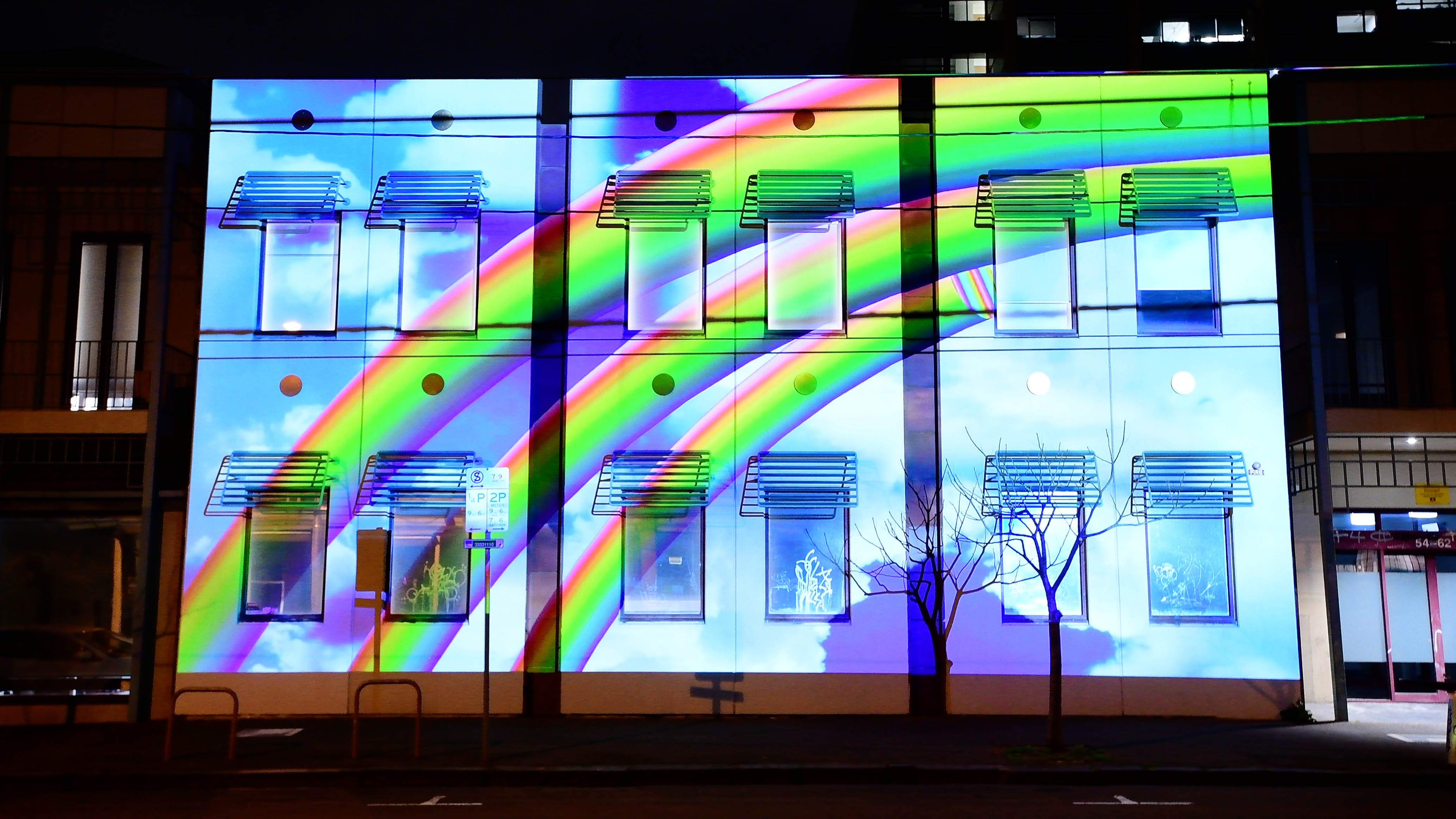Rainbow projected onto buildings at night 
