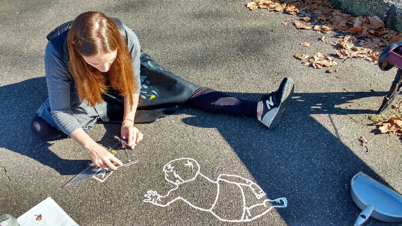 girl drawing with chalk on footpath