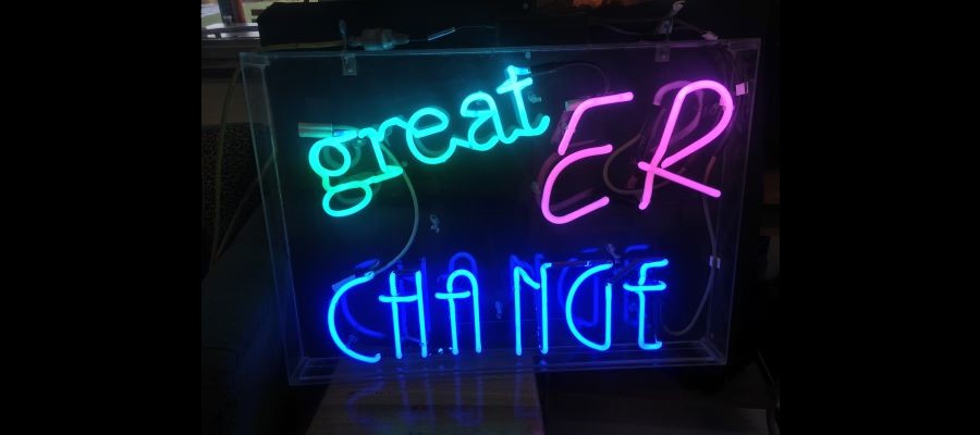 An image of three neon signs that spell out the words 'greater change'