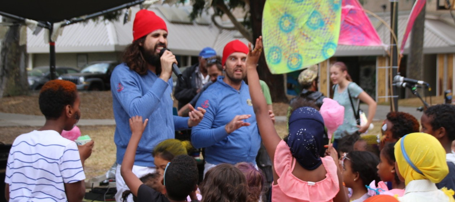 Comedians performing at the Collingwood Harvest Festival in front of a crowd of children.