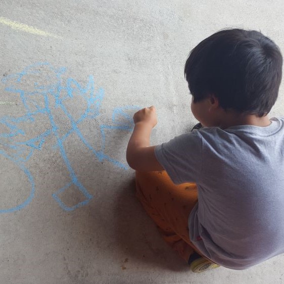 Ata draws on concrete with blue chalk