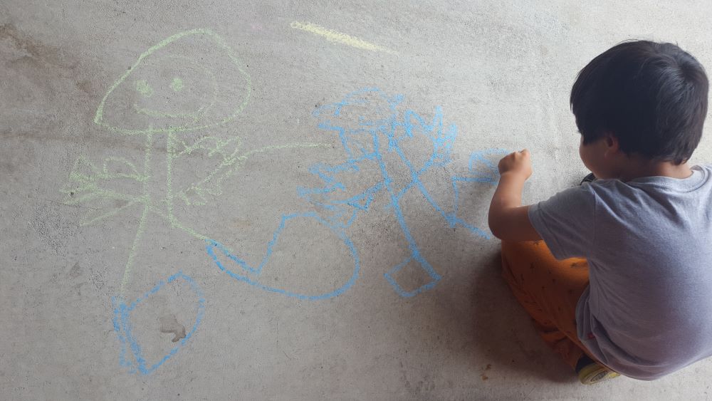 Image of a person drawing images of people on concrete
