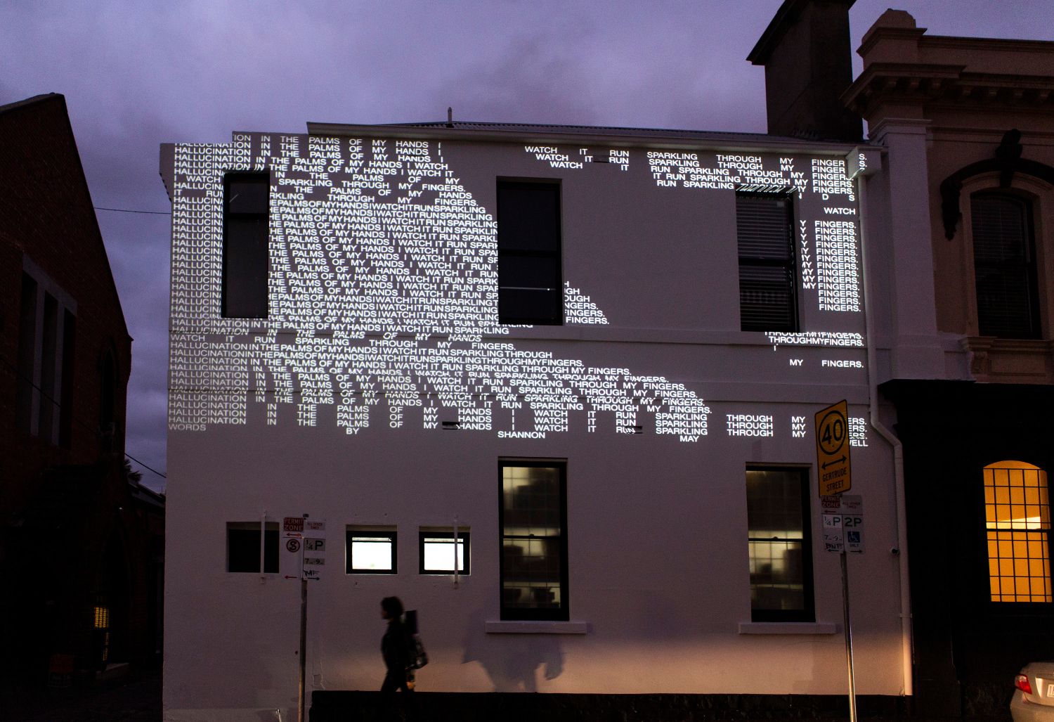 A white building with text projected onto the exterior walls. 
