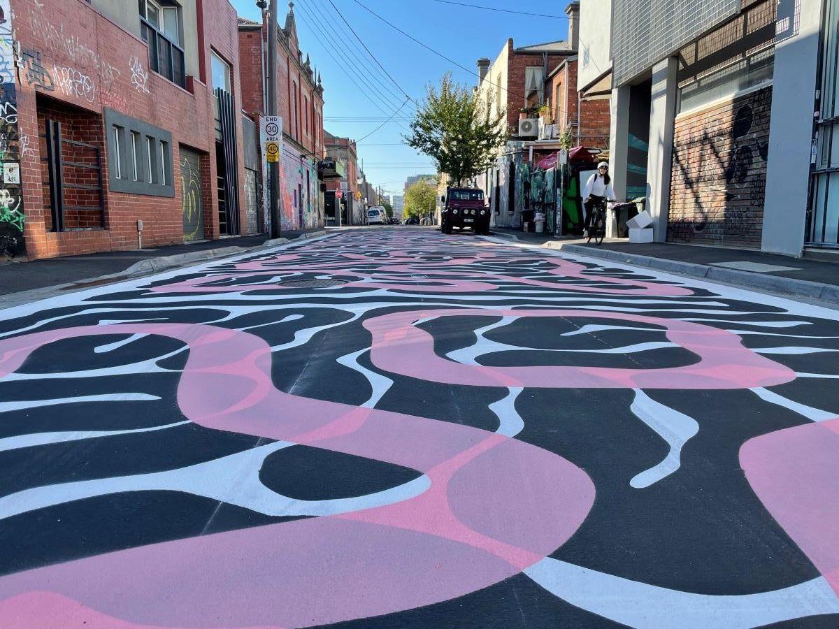 Otis Hope Carey's new mural on Rose St Giirrwaa. A beautiful pattern of pink, white and black lines span across the entire street.