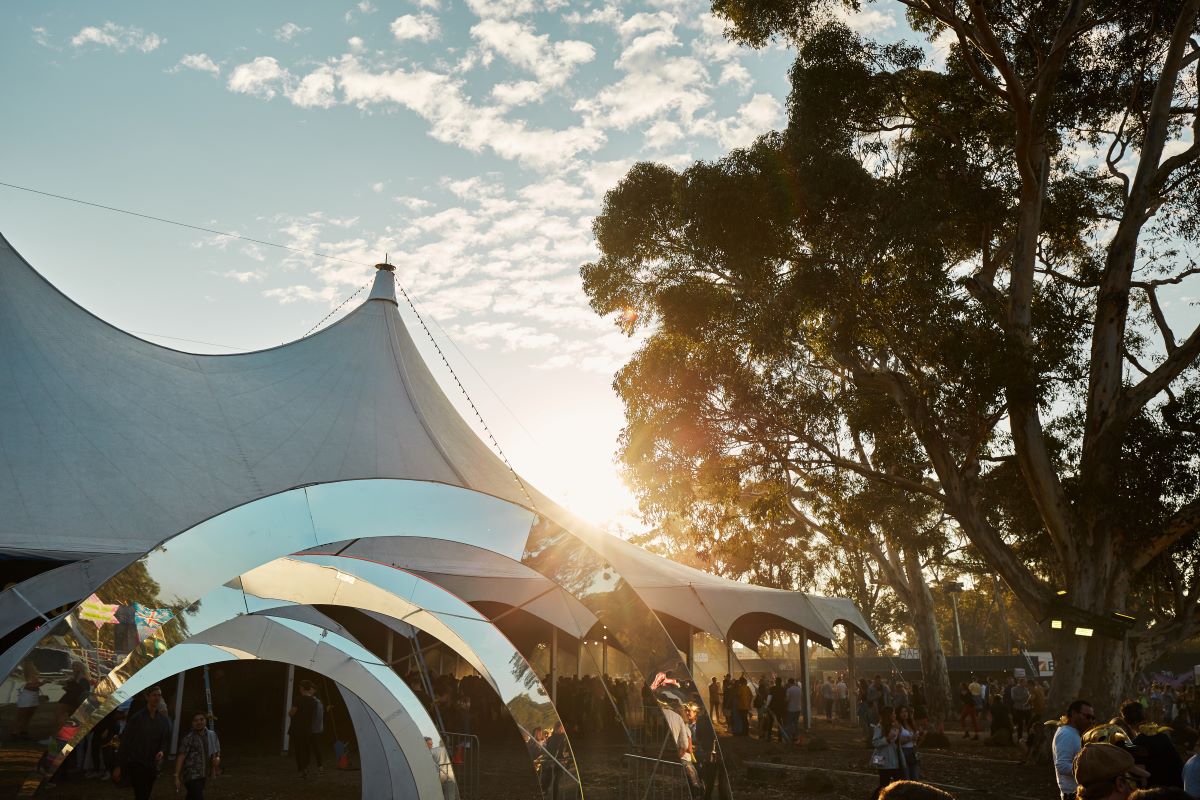 A festival tent with the sun shining from behind it.
