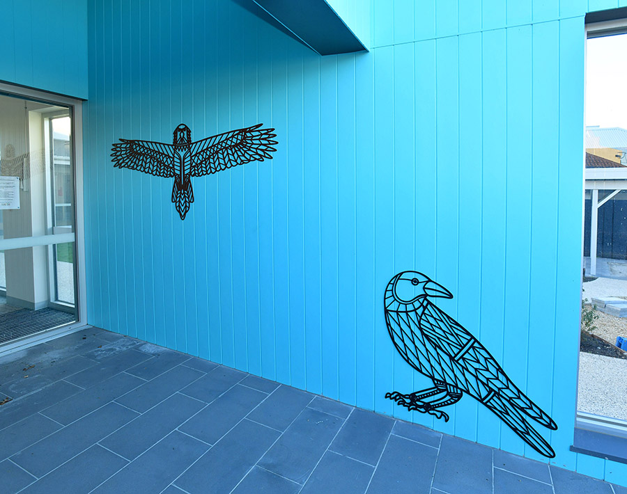 Two aluminium birds on playground entrance wall
