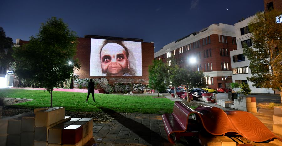 An image of a face with a another face super-imposed over the top, projected onto a brick wall in Peel Street.