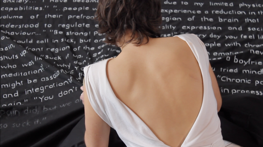 Image of woman from behind. She is facing a black canvas with white writing on it.