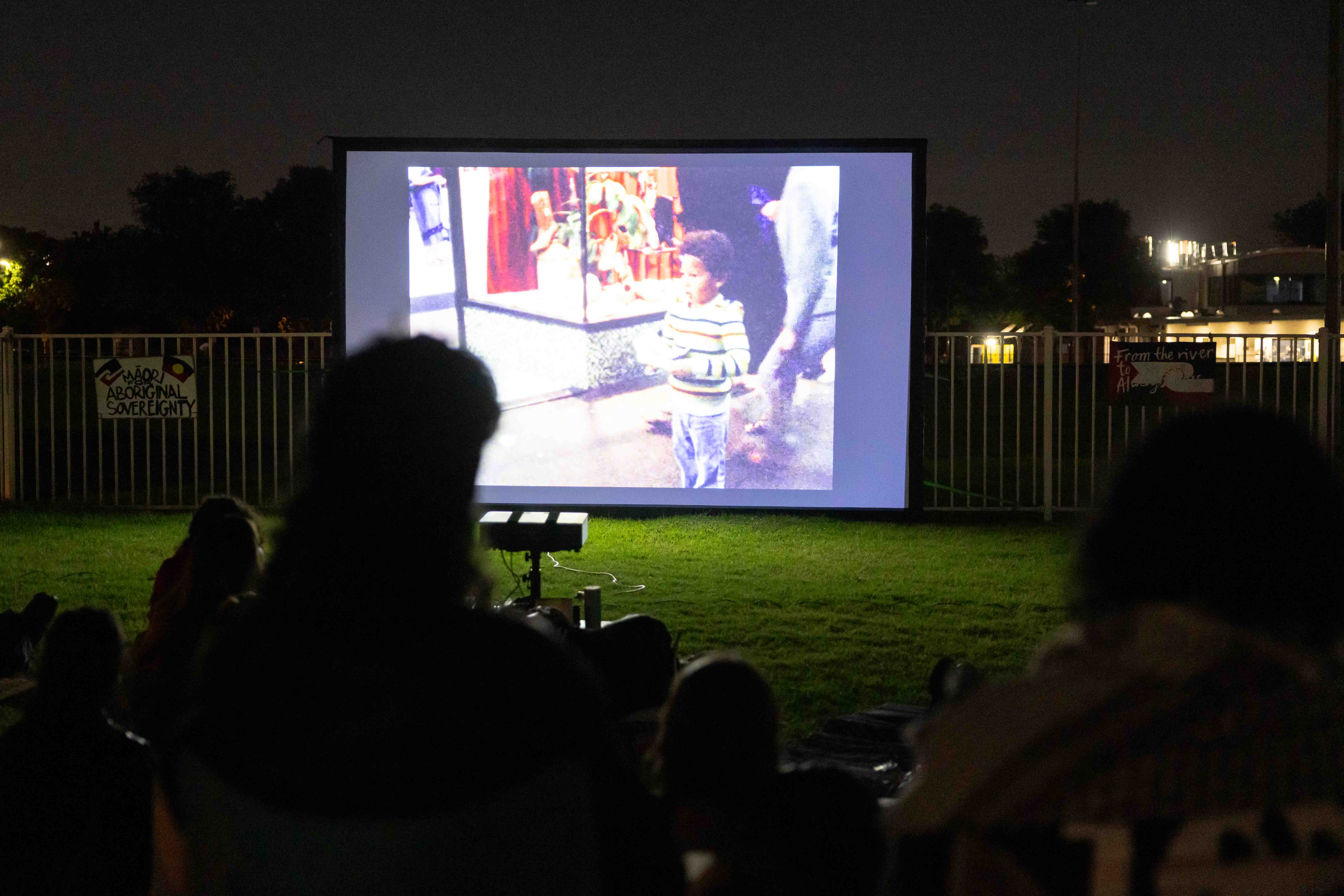 People watching an outdoor film on the grass.