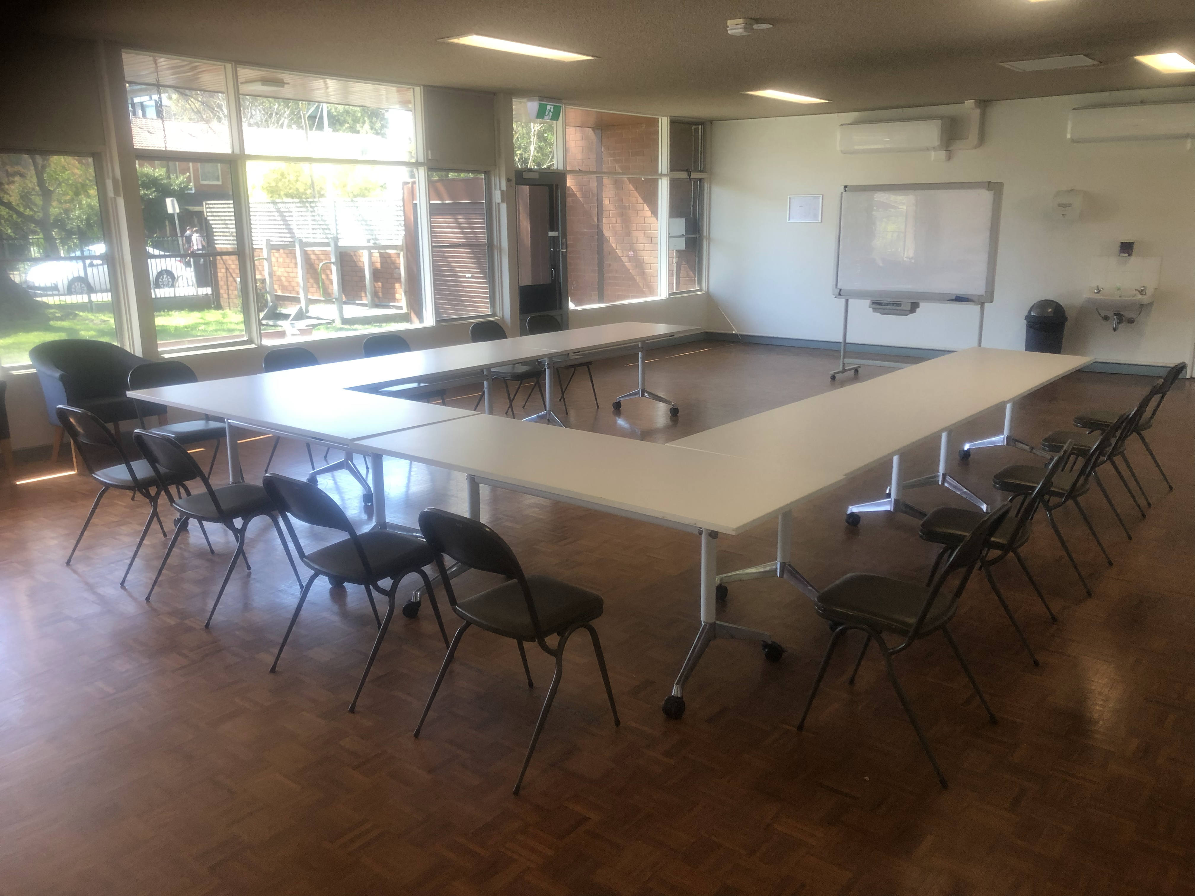 A community hall with white trestle tables setup in a u-shape