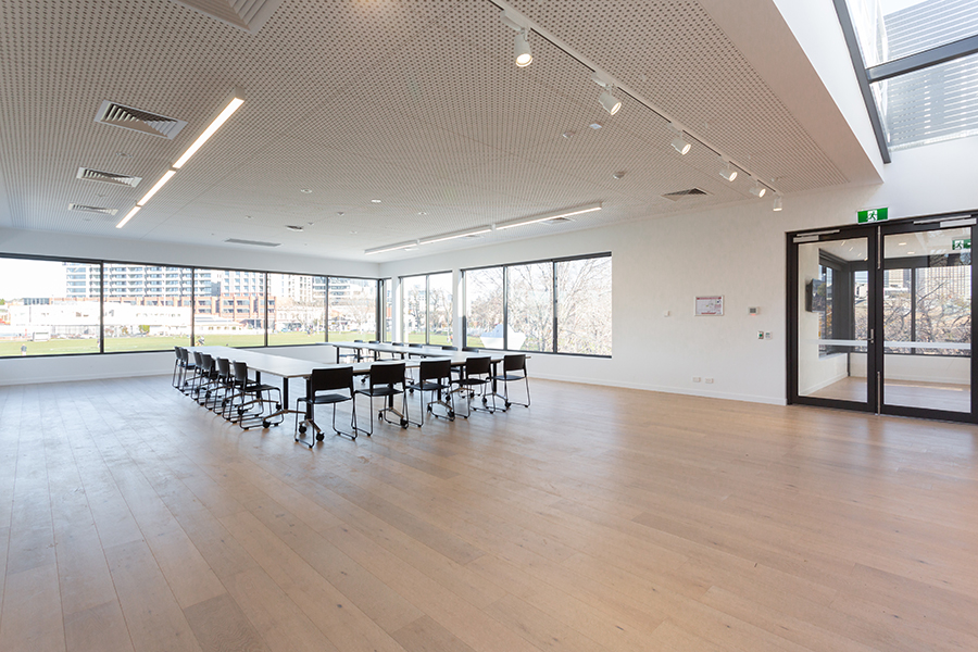 Wide picture of community room with tables and chairs setup for a meeting