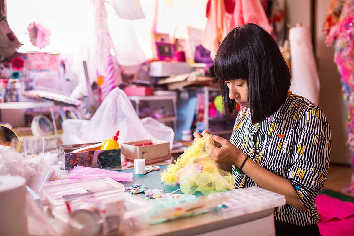 A women in a colourful room working with fabric