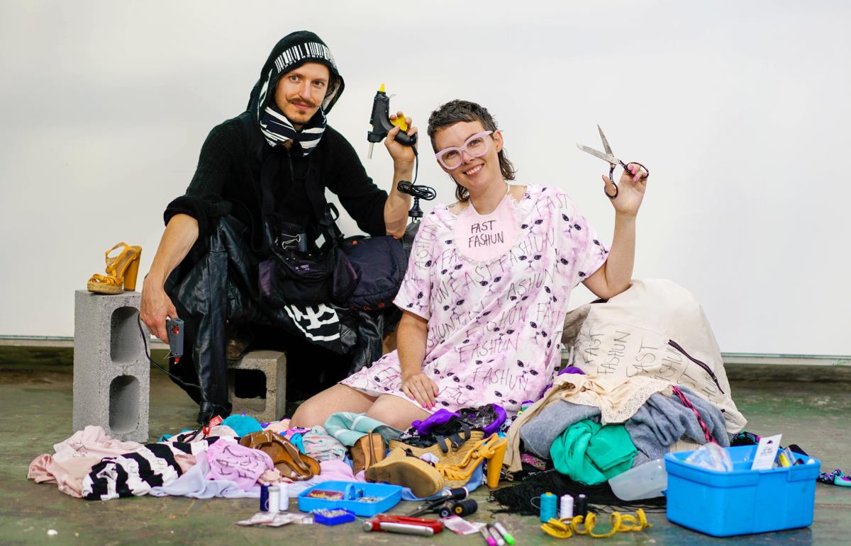 Fast Fashun artists posing with scissors and glue gun with a pile of fashion waste