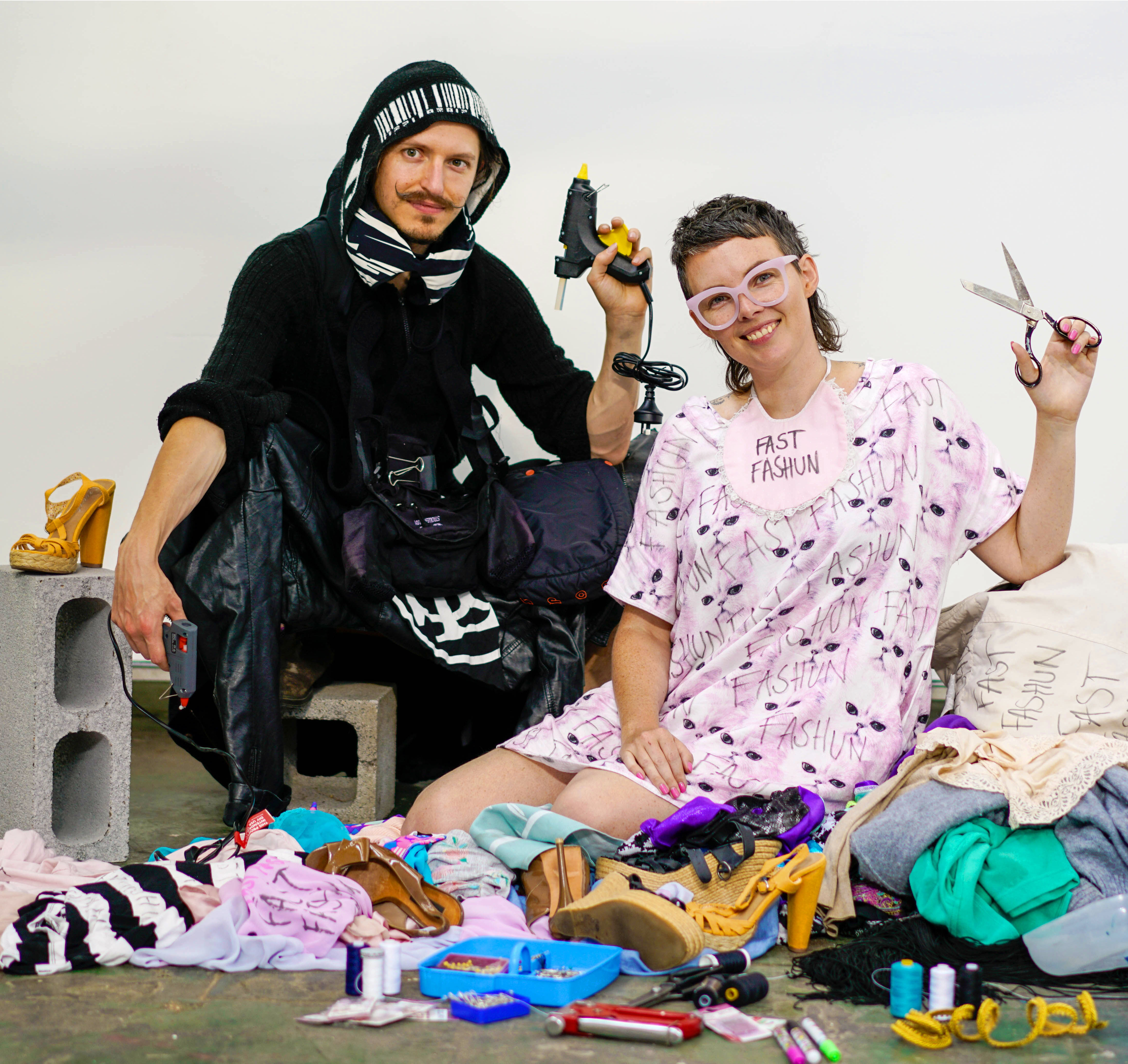 Fast Fashun artists posing with scissors and glue gun with a pile of fashion waste