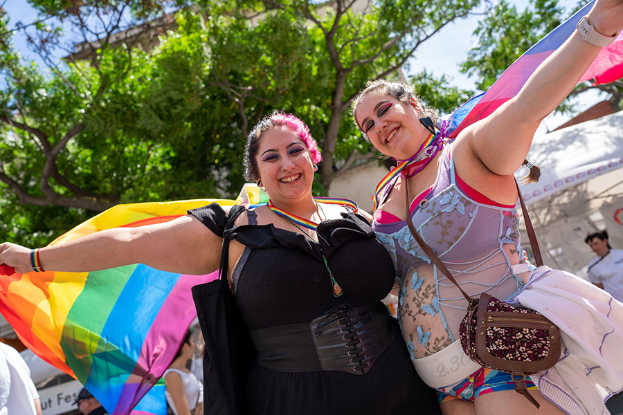 Two women waving rainbow flags at Pride Street Party
