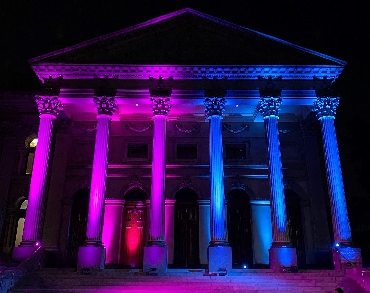 The facade of Fitzroy Town Hall lit up in multiple colours.
